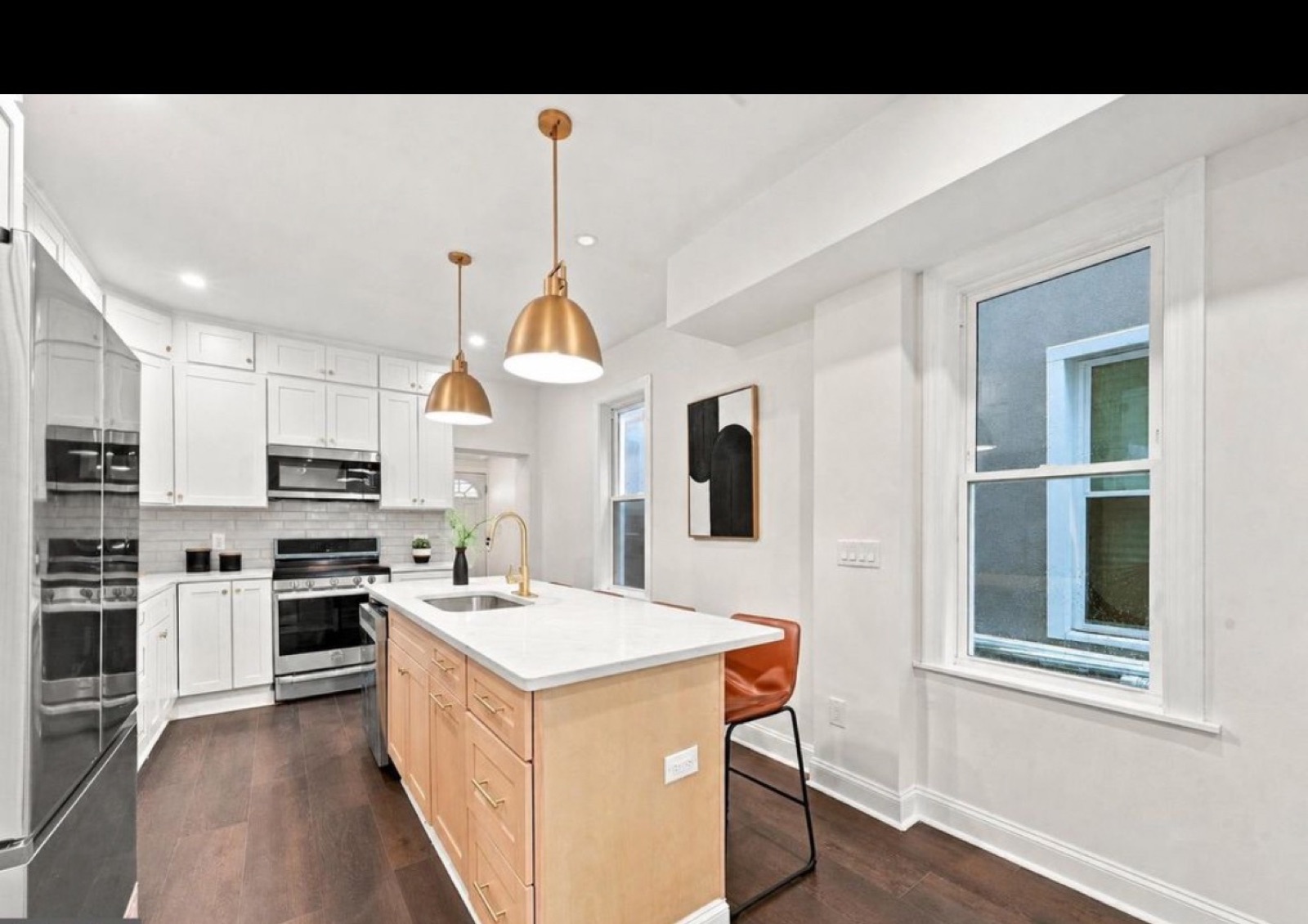 The same kitchen after our renovation: white cabinets, island, pendant lights