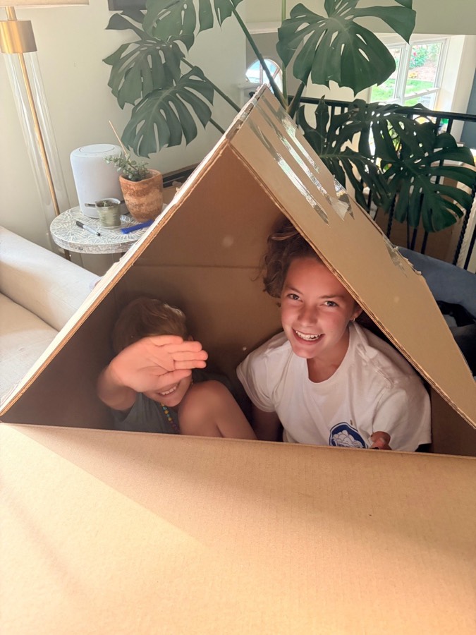 Aidan's kids playing in a cardboard house in the family living room